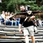 un fauconnier avec un rapace en vol devant des eleves assis